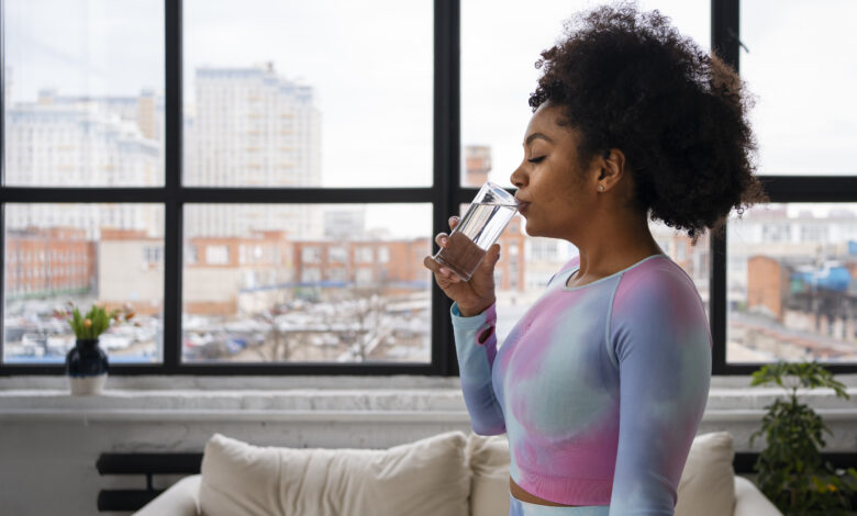 A Woman Drinking A Glass Of Water To Refresh Herself